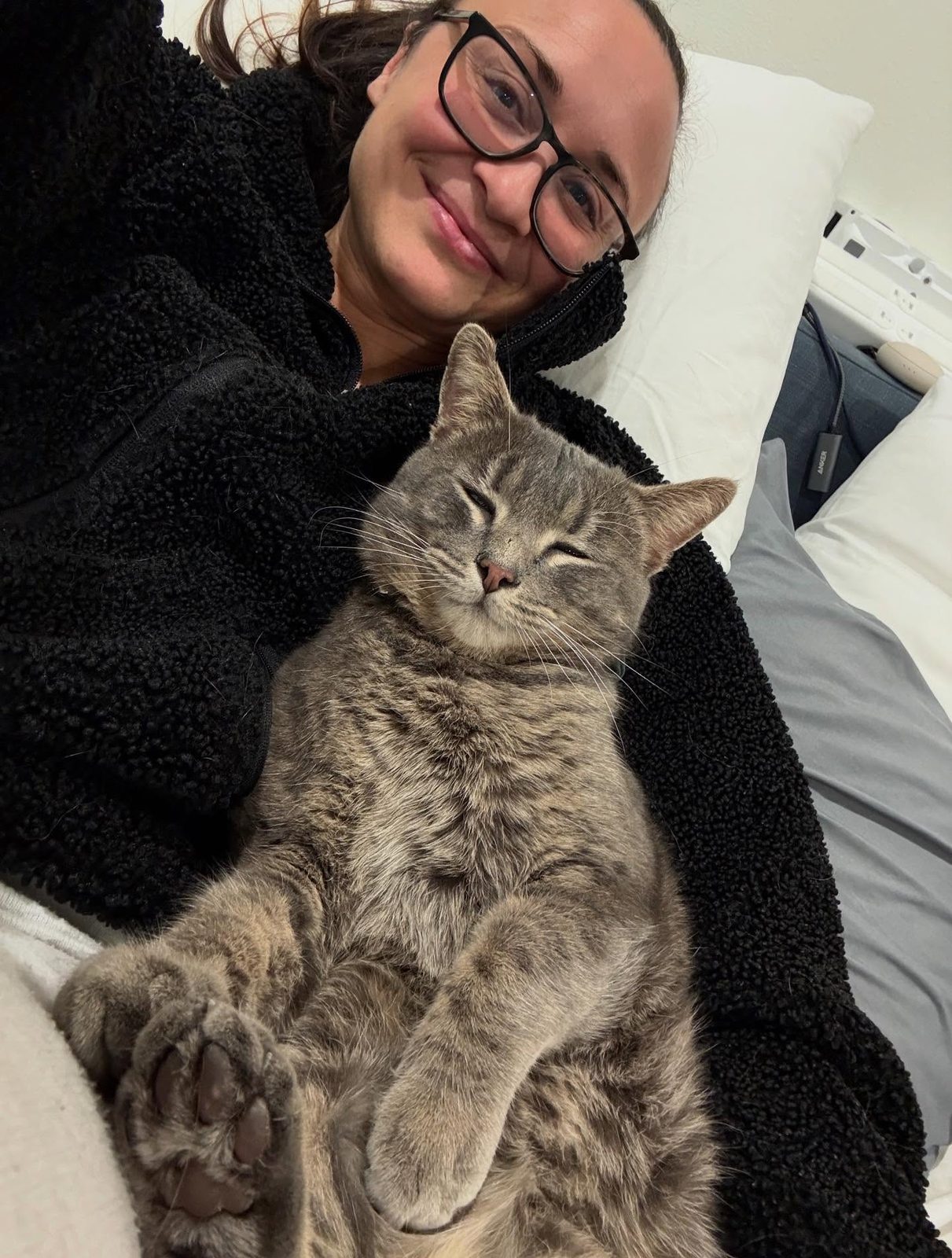 Amanda smiling with Chester the cat curled up on her chest